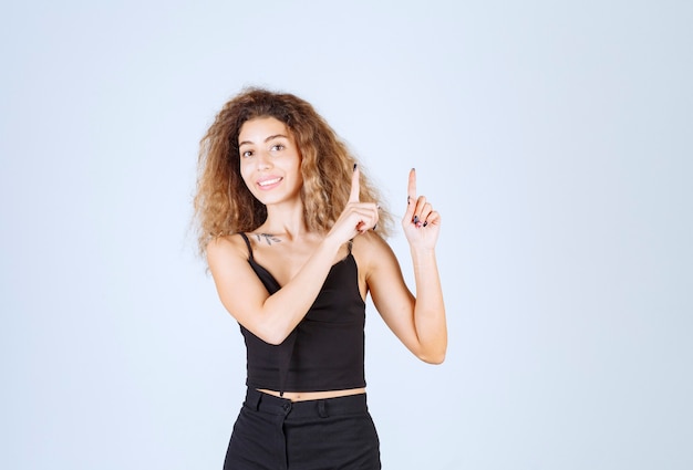 Blondiemeisje met krullende haren die naar boven wijzen.