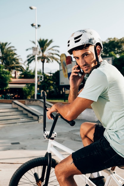 Gratis foto bmx-rijder die bij het middelgrote schot van de telefoon spreekt