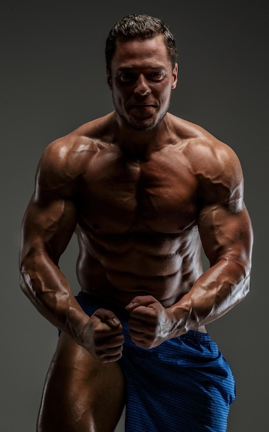 Bodybuilder poseren in studio. Geïsoleerd op grijze achtergrond.