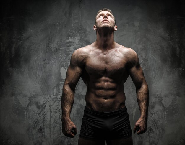 Bodybuilder poseren in studio op grijze achtergrond