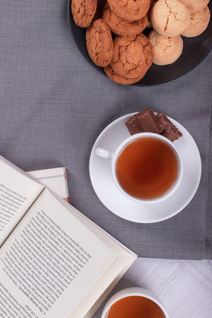 Boek, kopje thee en chocolade op de tafel