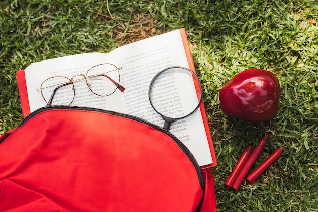 Boek met optische instrumenten in de buurt van rugzak en appel