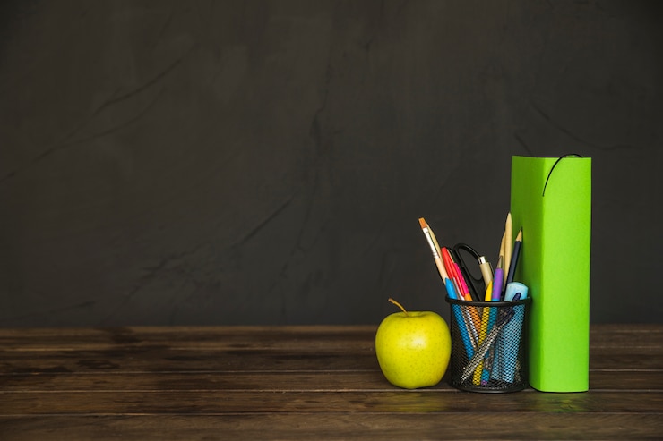 Gratis Foto boek met potloodbeker en appel op het bureau