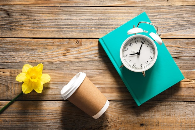 Gratis foto boek wekker papier beker en bloem op houten achtergrond bovenaanzicht