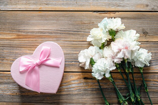 Boeket bloemen en hartvormige geschenkdoos op houten achtergrond plat gelegd