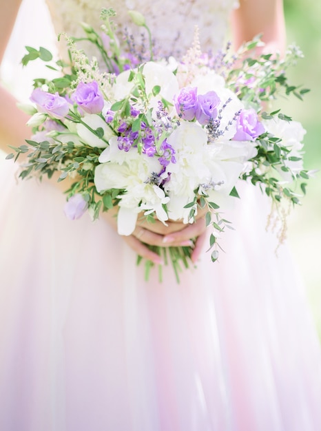 Boeket lavander en witte rozen in bruidens armen