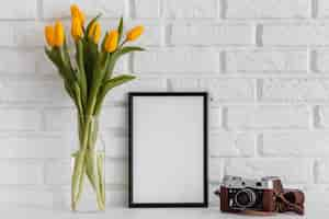 Gratis foto boeket tulpen in transparante vaas met leeg frame en camera