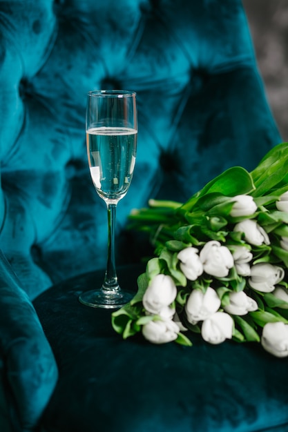 boeket tulpen witte bloemen met een glas champagne op een groene fauteuil