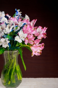 Boeket van roze en blauwe alstroemeria bloemen in glazen vaas.