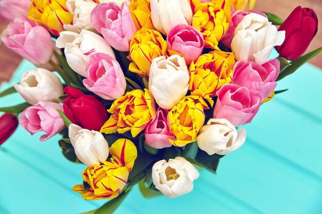 Boeket van verse veelkleurige tulpenbloemen op oude blauwe houten tafel