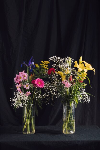 Boeketten van heldere bloemen in vazen met water