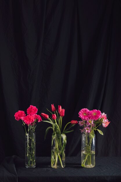 Boeketten van roze bloemen in vazen met water