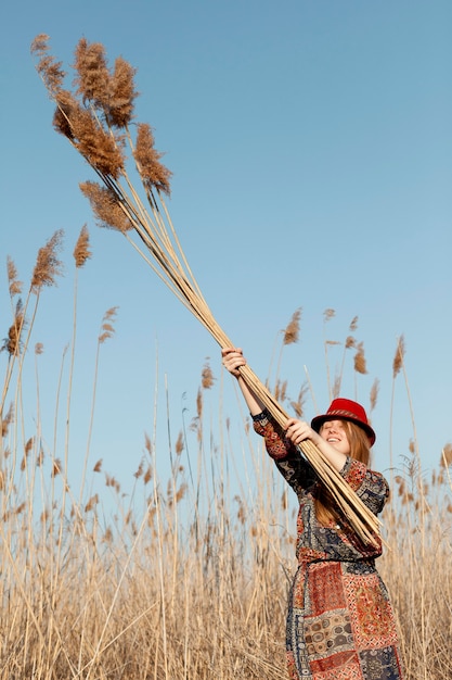 Gratis foto boheemse vrouw poseren met lang dood gras