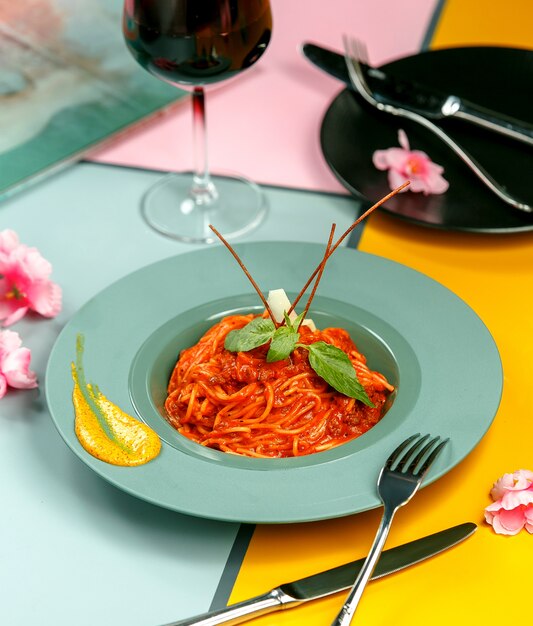 Bolognese spaghetti gegarneerd met basilicum in turquoise plaat