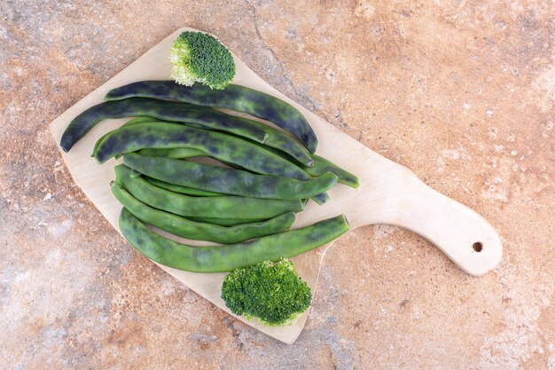 Bonenpulsbundel en een stuk broccoli op een marmeren oppervlak