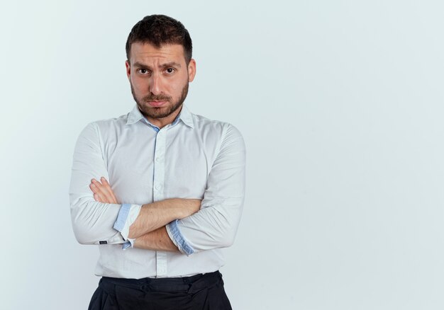Boos knappe man staat met gekruiste armen geïsoleerd op een witte muur