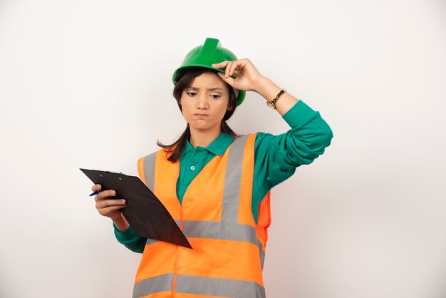 Boos vrouwelijke industrieel ingenieur in uniform met klembord op witte achtergrond.