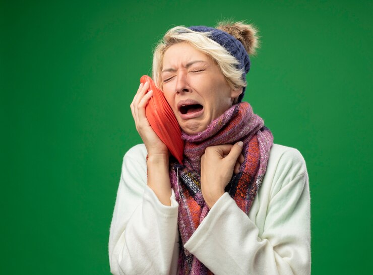 Gratis Foto boos zieke ongezonde vrouw met kort haar in warme sjaal en muts zich onwel voelen met waterfles om warm te huilen staande over groene achtergrond