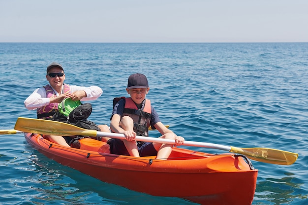 Boot kajakken in de buurt van kliffen op een zonnige dag. Kajakken in een rustige baai. Geweldig uitzicht. Reizen, sport concept. Levensstijl. Een blije familie.