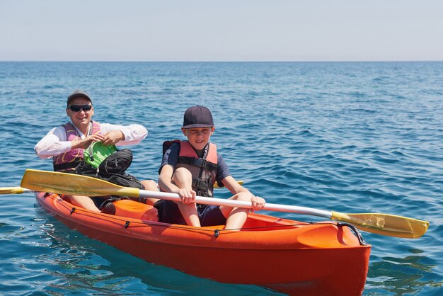 Boot kajakken in de buurt van kliffen op een zonnige dag. Kajakken in een rustige baai. Geweldig uitzicht. Reizen, sport concept. Levensstijl. Een blije familie.