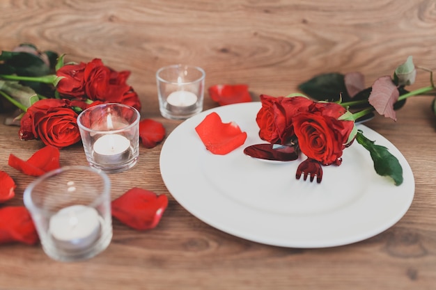 Bord met bestek en rozen en kaarsen op de achtergrond
