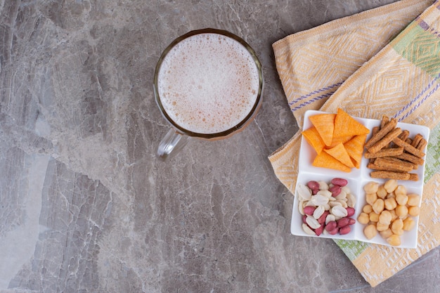 Gratis foto bord met verschillende soorten snacks en bier op marmeren oppervlak. hoge kwaliteit foto