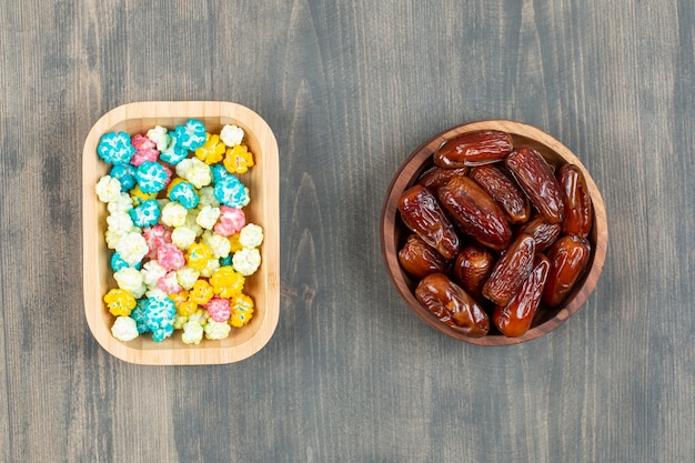 Borden met dadels en kleurrijke popcorns op houten oppervlak