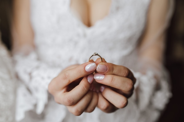 Borst van jonge bruid gekleed in trouwjurk met verlovingsring in handen met diamant