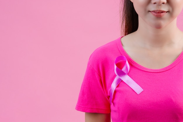 Borstkanker bewustzijn, vrouw in roze t-shirt met satijn roze lint op haar borst, ter ondersteuning van symbool borstkanker bewustzijn