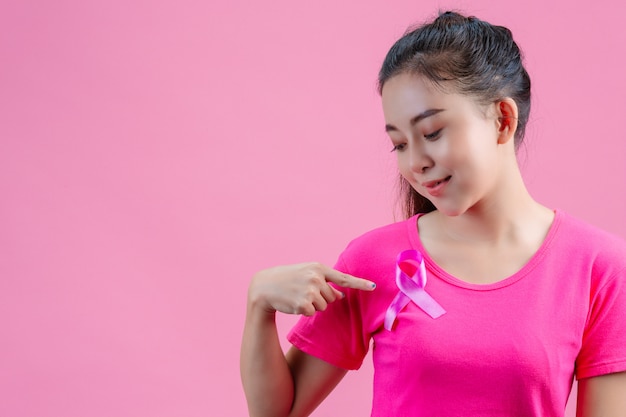 Borstkanker bewustzijn, vrouw in roze t-shirt met satijn roze lint op haar borst, ter ondersteuning van symbool borstkanker bewustzijn