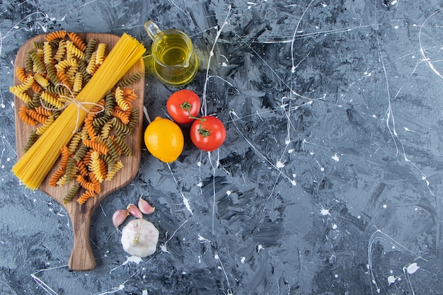 Bos van ongekookte spaghetti in touw met veelkleurige pasta en groenten.