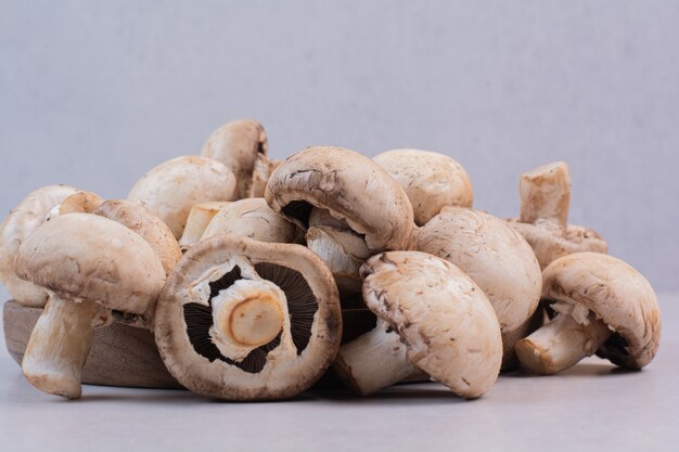 Bos van rauwe champignons op witte tafel.