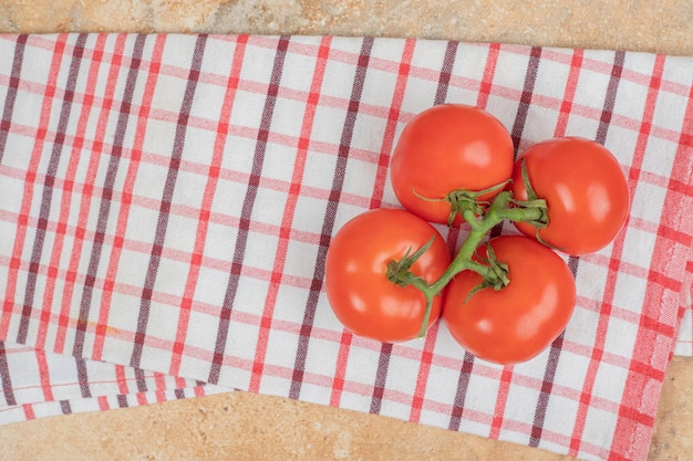 Bos van verse, rode tomaten met groene stengels op tafellaken