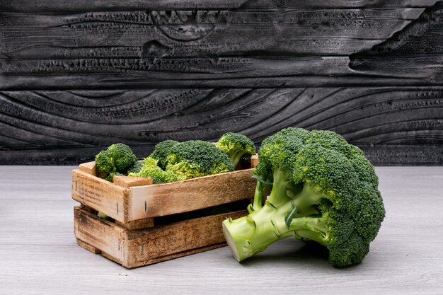 Bossen van broccoli in houten doos dichtbij de gehele verse broccoli