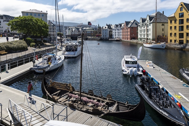 Boten op een brede waterkanaal omgeven door kleurrijke gebouwen in Alesund, Noorwegen