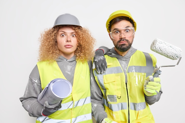 Bouwvakkers versieren appartement met verfroller en papieren blauwdruk dragen uniform