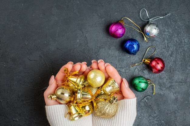 Boven weergave van hand met kleurrijke decoratieaccessoires op donkere achtergrond