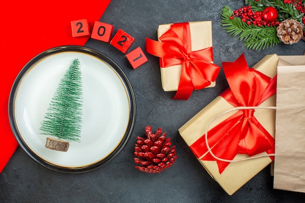 Boven weergave van kerstboom op een plaat conifeer kegel fir takken nummers mooie geschenken op een donkere tafel