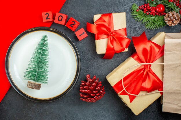 Boven weergave van kerstboom op een plaat conifeer kegel fir takken nummers mooie geschenken op een donkere tafel