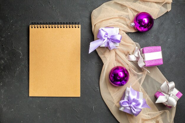 Boven weergave van kleurrijke geschenken decoratie accessoires voor het nieuwe jaar op naakt kleur handdoek en notitieboekje op zwarte achtergrond