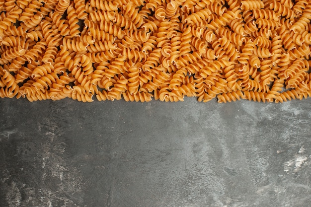 Boven weergave van rauwe Italiaanse pasta's op de bodem van de grijze achtergrond