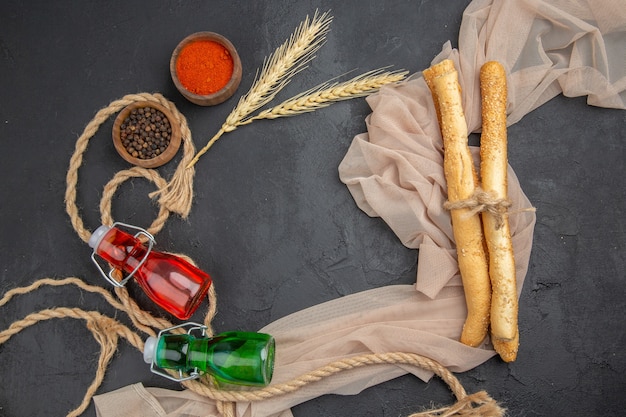 Boven weergave van verschillende paprika's en gevallen flessen op een handdoek op zwarte achtergrond