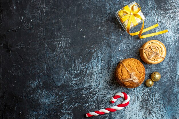 Boven weergave van Xmas achtergrond met gele geschenkdoos en koekjes snoep decoratie accessoires op donkere achtergrond