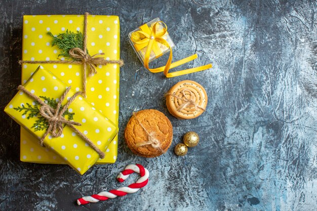 Boven weergave van Xmas achtergrond met gele geschenkdozen en koekjes op donkere achtergrond