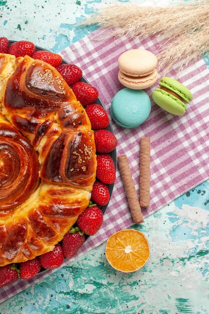 Bovenaanzicht aardbeientaart met Franse macarons op blauwe ondergrond