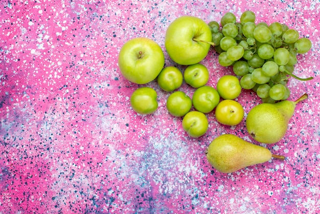 Bovenaanzicht appels en druiven samen met peren en kersen-pruimen op de gekleurde achtergrond fruit zoet zacht vitamine voedsel