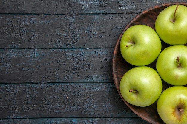 Bovenaanzicht appels op tafel zeven groengele appels in kom aan de rechterkant van donkere tafel