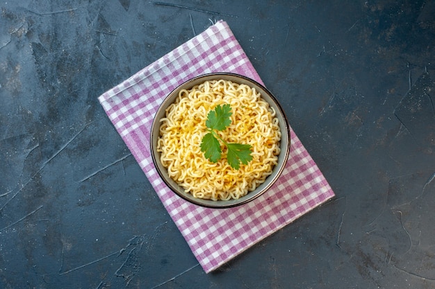 Bovenaanzicht aziatische ramen noodles met koriander in kom op roze en wit geruite keukenhanddoek op zwarte tafel