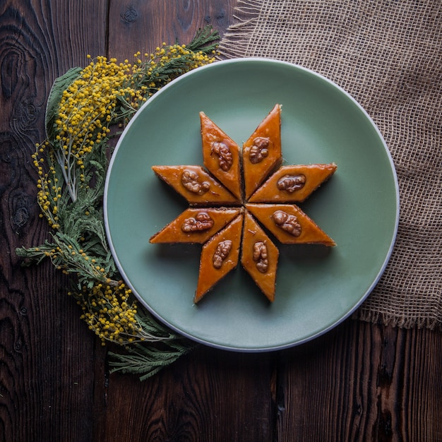 Gratis foto bovenaanzicht baklava met mimosa bloemen in ronde plaat