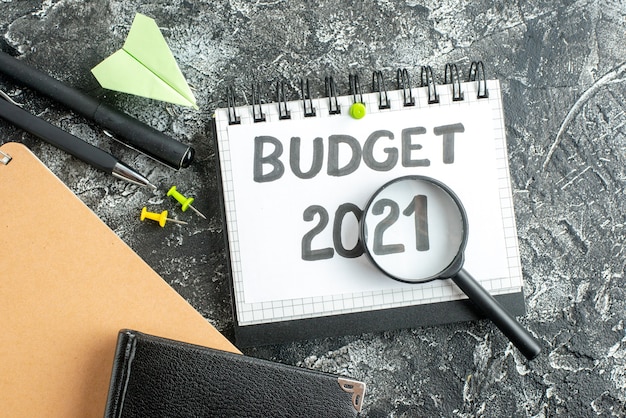 bovenaanzicht begroting notitie met pennen en vergrootglas op donkere oppervlaktekleur college student school geld zakelijk werk